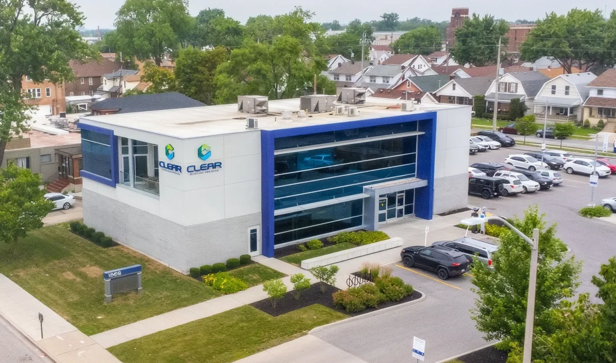 An aerial view of the Clear Medical Imaging centre, a two-storey building with a blue glass facade and a full parking lot