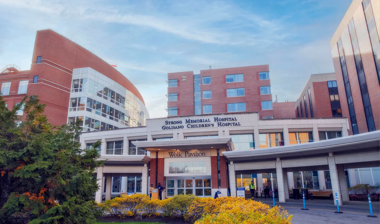 The Wolk Pavilion entrance of Strong Memorial Hospital and Golisano Children's Hospital, framed by autumn shrubs