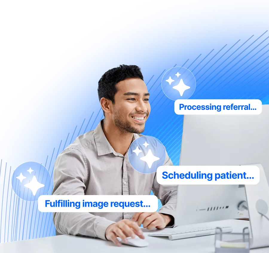 A smiling healthcare clerk works at his desktop computer while sparkle icons and status pills float around him, reading: processing referral, scheduling patient and fulfilling image request.