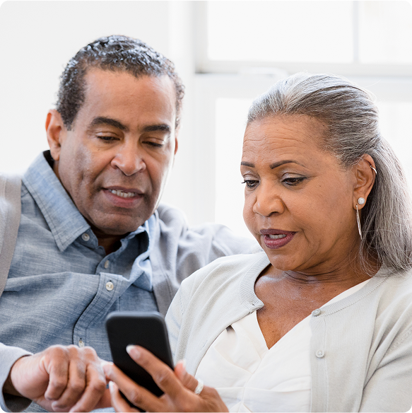 Two people are talking and looking at a smartphone together.