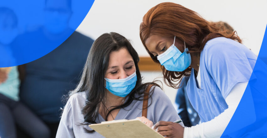 Healthcare professional showing female patient her chart in hospital waiting room wearing masks