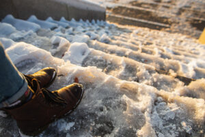 Danger of slipping. Female boots on rough slippery ice surface.