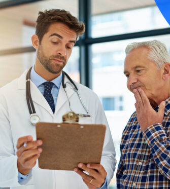 Doctor with clipboard reading charts to older man