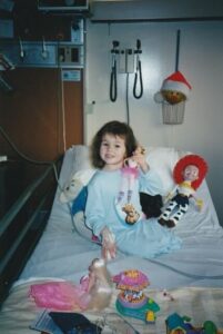 Marissa as a childhood cancer patient in the hospital with toys