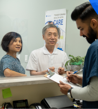 Nurse with two patients filling out forms at a hospital reception