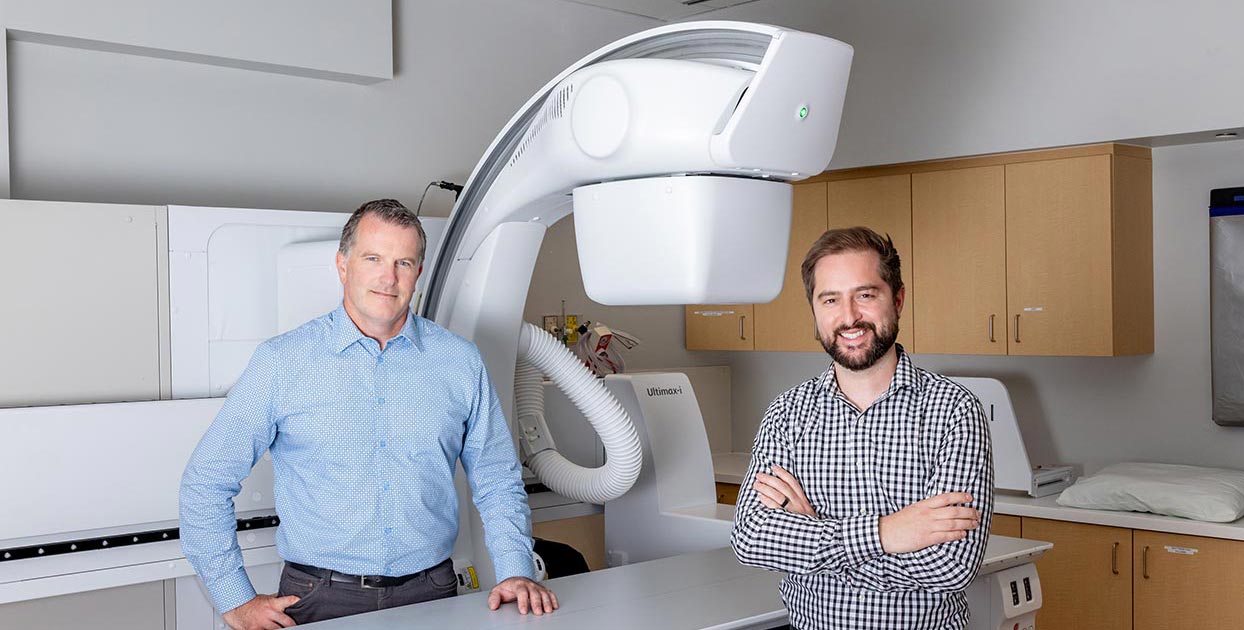 Two men stand beside an X-ray system in a hospital medical imaging room at St. Joseph's.